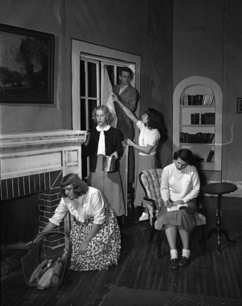East High School play, "The Goose Hangs High." The production staff is shown setting up for a performance. Pictured left to right: Lois Shoemaker and Margo Krogsund, of the art department, Jim Olberding, stage manager; Ann Slatter, properties chairman, and Yvonne Voss, student director.