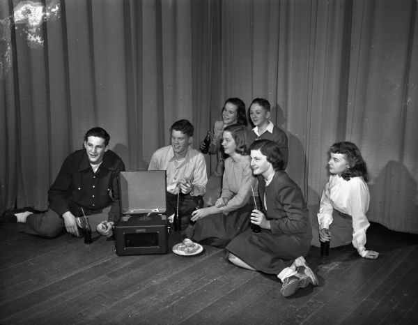 Some of the young people who attended the first of a series of informal parties for teenagers living in Maple Bluff. The party was at the Lakewood school. Seated in the front row, (from left) are: Jack Tomlinson, Bill Walker, Peg Huiskamp, Jane Botham and Sally Carlson. In the background are Diana Dean and Dick Plater.