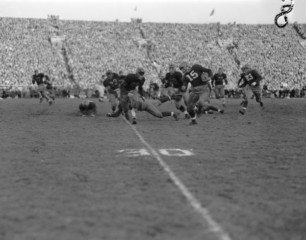 Gwynn Christensen (15) of the University of Wisconsin football team, at lower right, on a 25-yard run to the University of Marquette's 11-yard line that was disallowed by referees. Also in the picture are Marquette players Dick Melk (38,) Robert Ottoson (65,) and Brude Patton (23.) Wisconsin won the game 26-0.