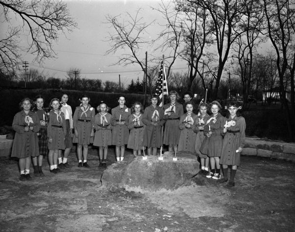 Eleven former members of Brownie Scout Troop 64 participating in a "fly-up ceremony in Glenwood Park where they became full-fledged Girl Scouts. Mrs. Glen (Bernice) Briggs is the scout leader for the new troop which will receive a number when they become registered.