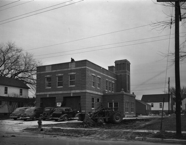 The nearly completed Madison fire station number 8, 409 North Street. There is a man on the roof holding a rope.
