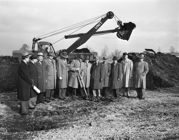 This ceremony at Truax Field signaled the start of construction of the 120-unit apartment project for war veterans by the Madison Housing Authority. Henry E. Reynolds, city council president, is shown turning the first spade-full of dirt on the 22 acre site. In the picture, left to right: Walter Johnson, city planning engineer; Allen Strang, architect; H.J. Loftsgordon, former MHA chairman; City Manager Howell; Reynolds; Horace W. Wilke, MHA chairman; W.L. Frazier, MHA executive director; Robert Strenger and M.B. Alexander, MHA members; Arthur Field, director of the Wisconsin Veterans Housing Authority; and Joseph J. Weiler, architect.