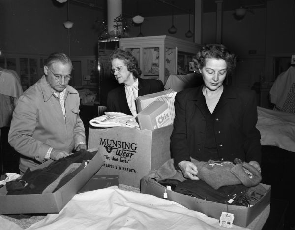 Joseph Rothschild, manager; Bertha Atkinson, buyer and Freda Kitson, saleswoman opened the children's and infants' department at Baron Brothers Department Store to children who had lost all their belongings in the fire at the tenement-type house at 15 South Bedford Street, where Florence Dinger and three of her children were killed. They are shown packing the snow suits, diapers, dresses and other things given to the children.