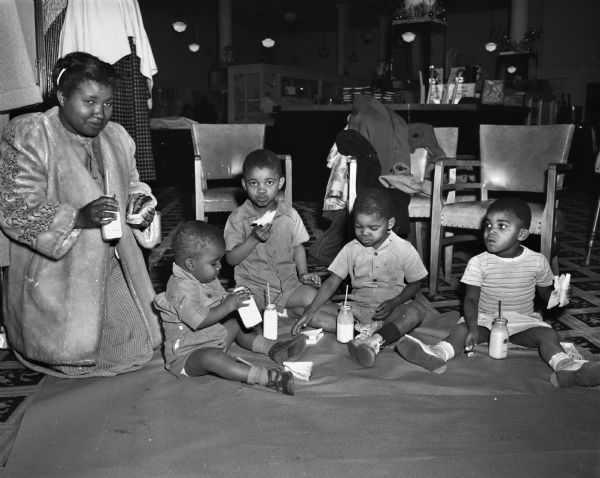 Annie Simmons and her four children are enjoying a "picnic" on the floor at Baron Brothers Department Store after the fire in the tenement-type house at 15 South Bedford Street, where Florence Dinger and three of her children were killed.