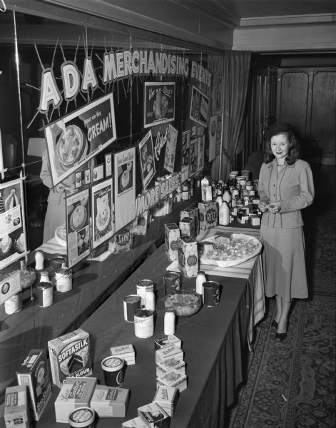 Leaders of the American Dairy Association met at the Loraine Hotel.  The ADA was organized in Madison in 1938.  Margaret McGuire, Alice in Dairyland, is shown with a display of food products. "ADA Merchandising Events Realize More Sales."