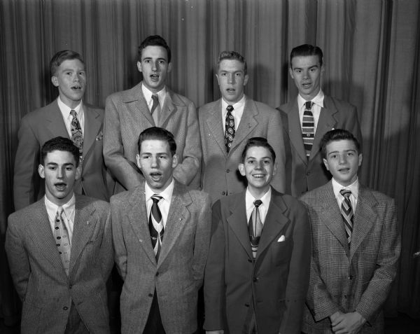 West High School Boys Double Quartet members are singing. The chorus members are, left to right  in the front row: Lowell Hall, Frank Wendt, Al Gay and Dave Moran. In the second row, left to right are: George Crownhart, Dave Henry, George Steinmetz and Burr McWilliams.