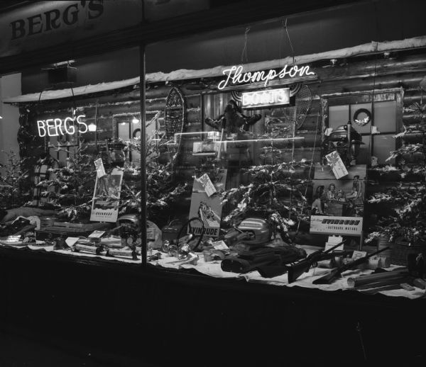 Berg's Sporting Goods window at the corner of 2123 Atwood Avenue and Division Street, featuring Thompson boats and Evinrude motors.