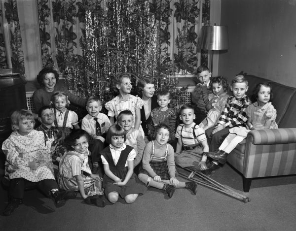 Two Alpha Gamma Delta Sorority members with group of children from the Washington Orthopedic School during a Christmas party. Sorority members are at left, Lois ?, Wauwatosa, and at right, Delores R. Silverness, Horicon, Wisconsin.