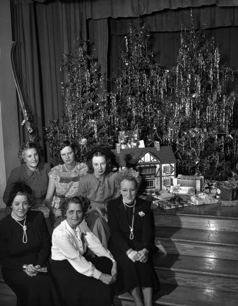 Six members of the East Side Women's Club with a dollhouse to be given to the chi:ldren at the Morningside sanatorium. Seated in front, left to right, are Mrs. Namen Torgeson, Mrs. V.H. (Pauline) Stoker, and Mrs. Norman Wang, club president. In the second row, left to right, are: Mrs. Arthur Swan, Mrs. George Peck, and Mrs. Norman (Jean) Scovill.