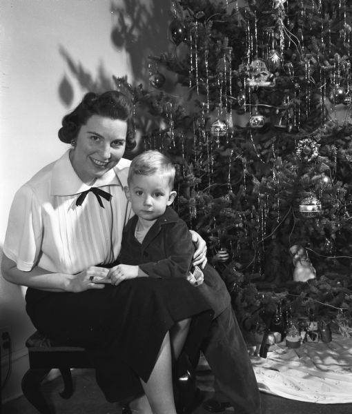Mrs. John Carrier Weaver, Minneapolis, Minnesota, and her two-year-old son, Andrew, sitting by the Christmas tree while visiting in the home of Professor Andrew Weaver, 126 North Spooner Street.