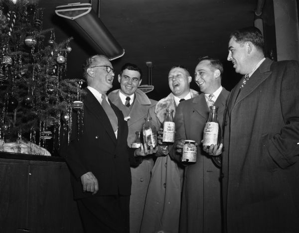 "Roundy"  with four men from Wisconsin Dells holding milk bottles full of donated money they collected for "Roundys" Fun Fund. Left to right are "Roundy" Coughlin, Jack Kelly, Jimmy Wimmer, Nig Kinney, and Tommy Wilbern.