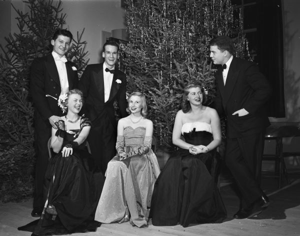 Three couples in front of two Christmas trees at the holiday benefit dance held at the Turner Hall. The seated girls are, from left, Patricia Albrecht, Julianne Weiss, and Patricia Patterson. Their escorts, from left, are Richard Johnson, Hobart S. Johnson II, and Toby Sherry.