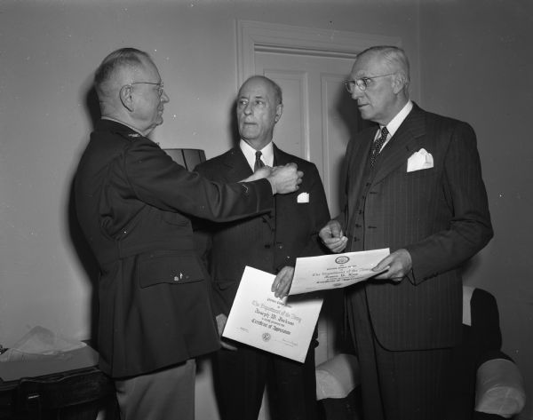 Col. John Ehlert, headquarters, Fifth army, Milwaukee, presented "certificates of appreciation" to Joseph Jackson, executive director of the Madison and Wisconsin foundation, and James Law, chairman of the state highway commission and former Madison mayor, for their contributions to the war effort and army-community relations.