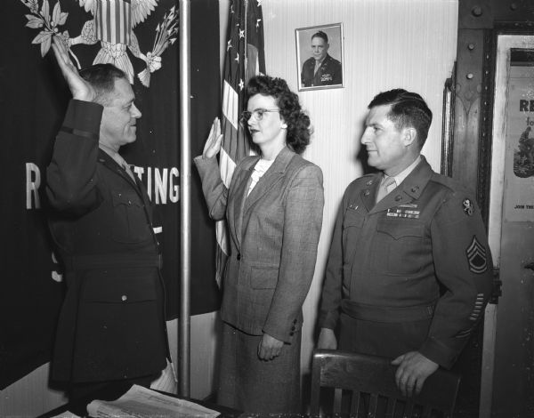 Glady McConochie, daughter of Mr. and Mrs. Chris McConochie of Pardeville, in center, taking her oath from Elmer H. Gibson, at left, commanding officer of the United States Army and Air Force recruiting station in Madison. At right is Tech. Sgt. William E. Burtis, who recruited Miss McConochie as the first woman in the area to enlist in the Women's Air Force (WAF}.