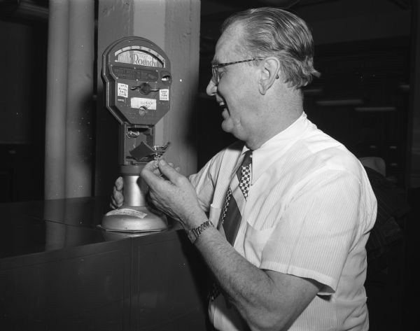 Roundy Coughlin, <i>Wisconsin State Journal</i> sports reporter, standing with the parking meter he uses to raise money for his "Roundy's Fun Club" for handicapped children. The meter is good for six minutes for a nickel, and has his picture on the red flag that reads "put a nickel in and keep this mug down".