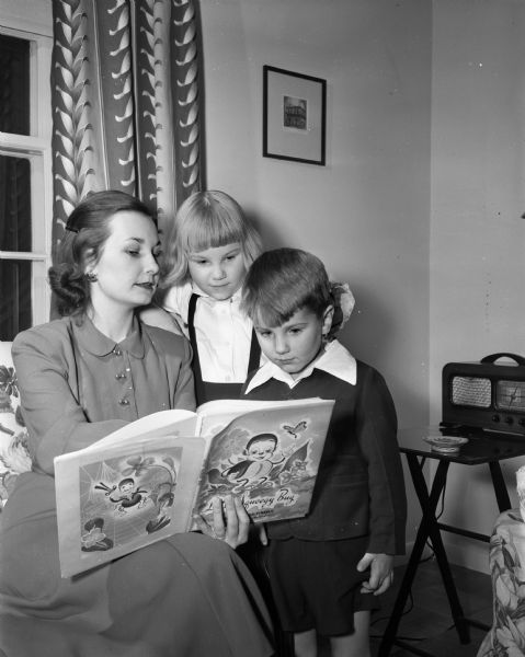 Mrs. J. Riley (Anne) Best, Eagle Heights apartments, reading a book to her two children, Sally 6, and Steven, 4. The family is new to the area, having moved here from Louisville, Kentucky when Mr. Best was named assistant track coach at the University of Wisconsin.
