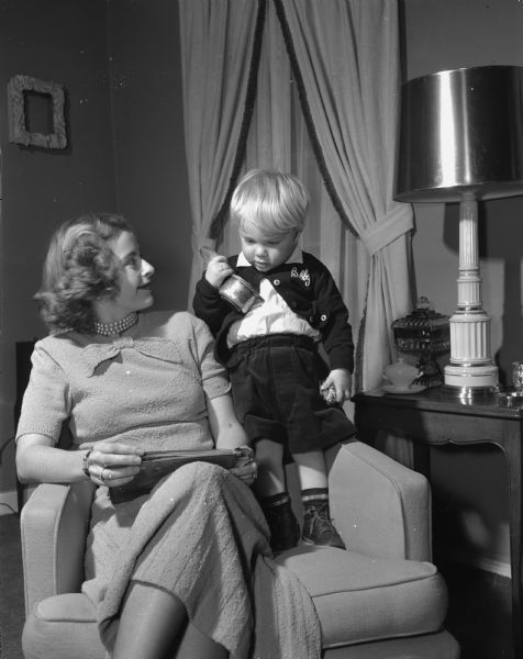 Mrs. Robert C. (Phyllis) Beck and her son Bobby, 20 months, in the living room of their home in Lakeview Heights. The family recently moved to the city from Toledo, Ohio. Mr. Beck grew up in the area, and his late father was Howard H. Beck of Maple Bluff.