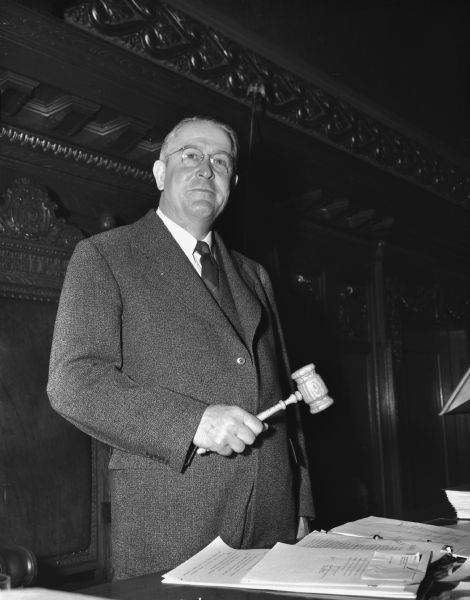 Portrait of Alex L. Nicol, Wisconsin Assembly Speaker, wielding a gavel in the Assembly Chambers of the Wisconsin State Capitol at the opening of the 69th session of the Wisconsin Legislature.