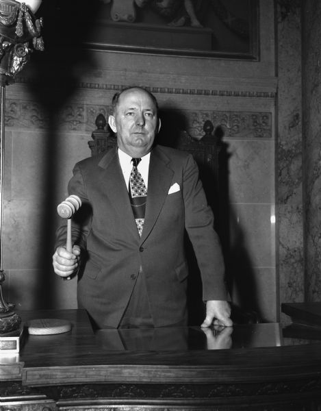 Portrait of Senator Frank Panzer wielding a gavel in the Senate Chambers of the Wisconsin State Capitol at the opening of the 69th session of the Wisconsin Legislature.