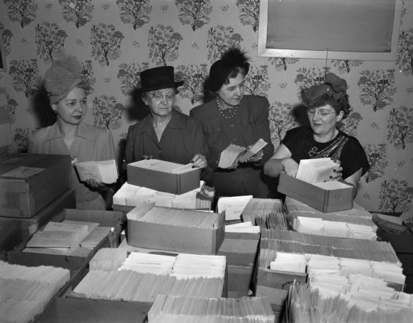 Mable Barton, Leone Hartman, Dorothy Mueller, and Dr. Christine Thelen, all members of the Madison Business and Professional Women's club, with thousands of envelopes, which the club members addressed and "stuffed" as their contribution to the "March of Dimes" campaign for infantile paralysis.