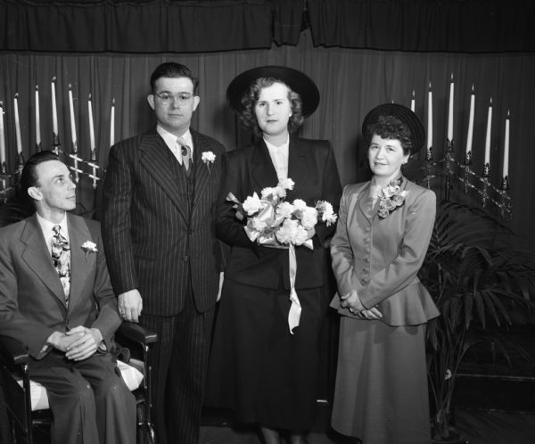 The Wallestad-Stolle wedding party, left to right: Fred Woolsey, best man; Phillip Weston Wallestad, groom; Ursula Stolle, bride; and Mrs. John Wallestad, stepmother of the groom and matron of honor. The wedding took place at Lake View Sanatorium, where the groom was a patient. The best man is in a wheelchair because of an accident.