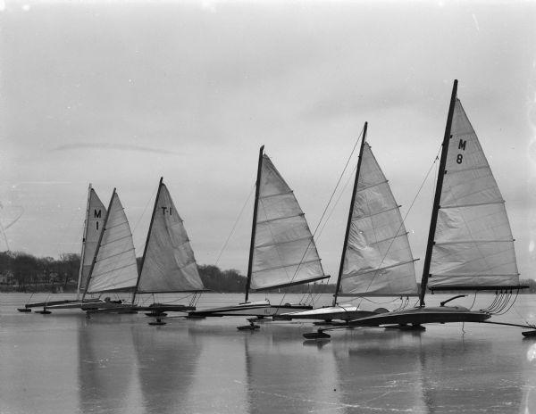 Six iceboats from the Four Lakes Ice Yacht Club fleet on Lake Monona.