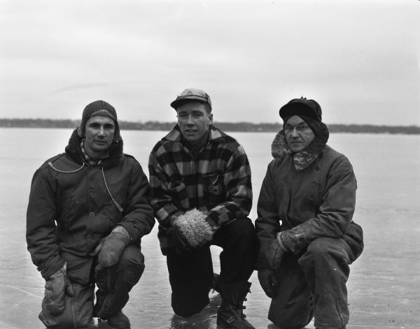 Group portrait of three iceboat skippers, all members of the Four Lakes Ice Yacht Club. Pictured on frozen Lake Monona from left to right are: Martin Raynoha, Bill McCormick, and Walter Haspell. Haspell was a veteran skipper, having piloted iceboats for more than four decades.