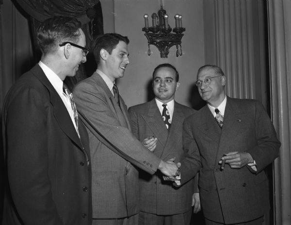 Lee Baron, of Baron Brothers Department Store, being congratulated by his boss, Joe Rothschild, on being selected Madison's "outstanding young man" of 1948. Left to right: Charles O. Vau Dell, Junior Chamber of Commerce; Lee Baron; Horace Wilkie, "outstanding young man" of 1947; and Joe Rothschild.