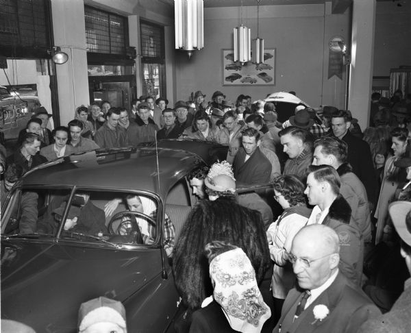 Crowd of people looking at a 1949 model Chevrolet automobile at Hult's Capital Garage, 609 East Washington Avenue.