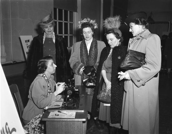 Four ladies observing a woman demonstrating on a sewing machine at the University of Wisconsin Farm and Home Week.