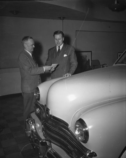 Marshall Straus, (right) being presented with a brand new Kaiser automobile that he received as part of his $13,500 worth of prizes he won from the "Stop The Music" radio show on Jan. 16. Also shown presenting the car and a 30,000 mile guarantee is O.T. Koch (left), president of Koch Motors.