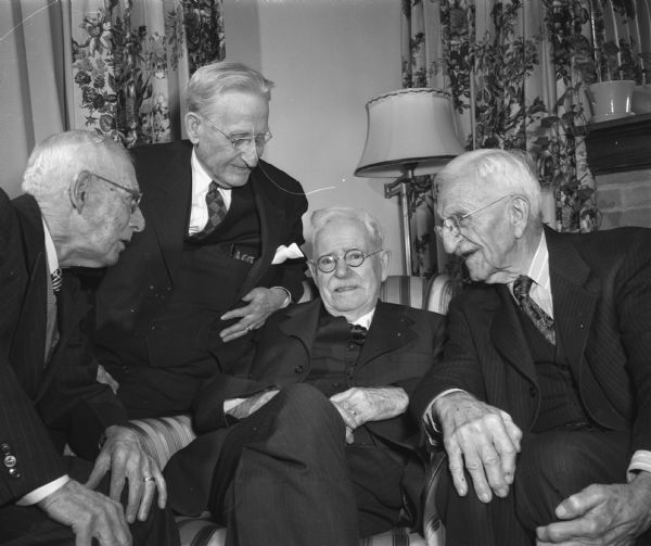 Will N. Wells, of the Wells Printing Company, celebrating his eighty-fourth birthday with friends. Left to right: John G. MacFarland, an actor; J.J. McManamy, retired attorney; Will N. Wells, and Gerrit Corscot, abstract business office. John G. MacFarland was a favorite actor in the days of the Al Jackson Players. J.J. McManamy, a retired attorney, was one of Wells' close political associates. Gerrit Corscot had an abstract service, Dane County Title Company, next to Wells Printing across from the Dane County Courthouse.