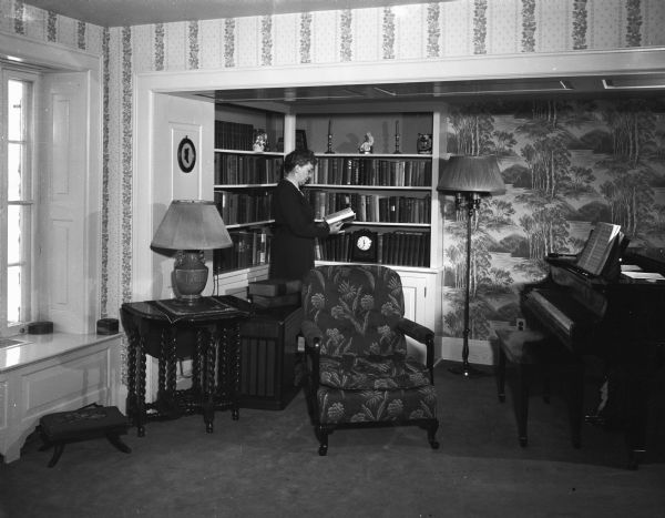 The living room of the historic stone farmhouse at 901 University Bay Drive, recently renovated by Freda Keys Winterble. The house was named "Keystone" after her family. The farm house was built by William J. Petherick in 1853. (It is now the Max Kade Institute for German American Studies". Freda Winterble is reading a book in front of a bookshelf. 
