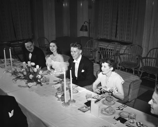 King Clayton Hahn, Milwaukee, and Queen Violet Norrman, Williams Bay, at the head table of the dinner for the Junior Prom at the Great Hall of the Memorial Union. Seated with the king and queen are Dean Paul L. Trump and Mrs. Paul (Elva) Trump.