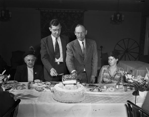 Professors Vernon Carstensen (left) and Merle Curti, with their wives, cutting the ceremonial cake at the testimonial luncheon in their honor as authors of "The History of the University of Wisconsin".