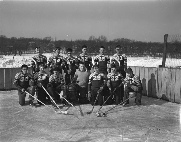 Group portrait of the undefeated West High School hockey team in uniform with hockey sticks posing on the ice at a rink outdoors.