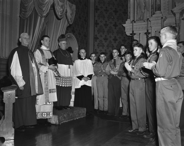 Bishop William P. O'Connor of the Madison diocese leading the Scout Convocation at St. Raphael's cathedral. Twenty scouts received  the Ad Altare Dei medal at the ceremony. The diocesan clerymen taking part are (left to right) Rt. Rev. Msgr. William Mahoney, St. Raphael's; Rev. Jerome Mersberger, St. Bernard's; Bishop O'Connor; Rev. Howard Finnegan, Platteville; and Very Rev. Edward Kinney, chancelor of the diocese.