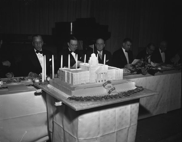 Birthday cake in the shape of Bascom Hall in front of the speakers table at the University of Wisconsin centennial birthday banquet in the Great Hall of the Memorial Union.