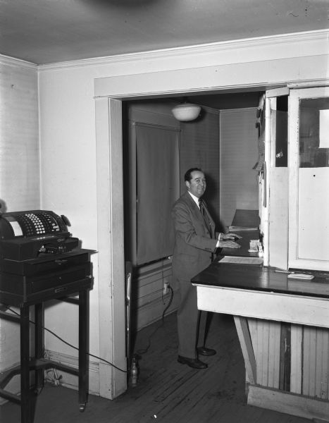 William Aspinwell, University of Wisconsin business manager of athletics, standing at the ticket window of the old ticket office at 711 Langdon Street.