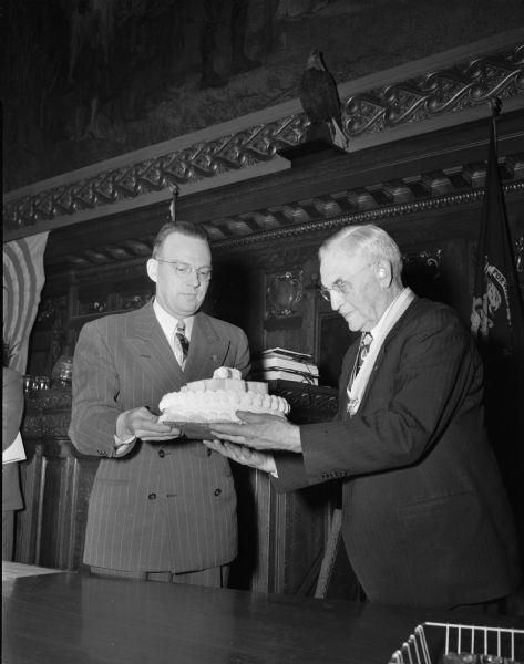 Harlan Nicholls, president of the Four Lakes Boy Scout council, is shown, left, as he presents a birthday cake to Chief Justice Marvin Rosenberry in observance of his 81st birthday and 33rd anniversary of his judgeship, and the 39th anniversary of the founding of the Boy Scouts of America.