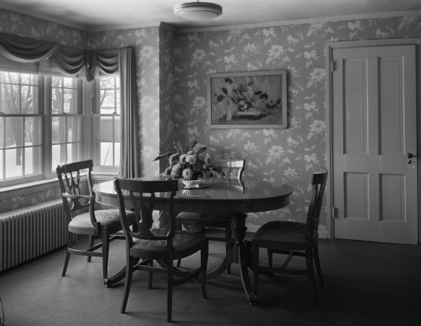 Interior view of the dining room in the home of Dr. Isadore Schultz. The turquoise and white wallpaper sets off the blond mahogany furniture.