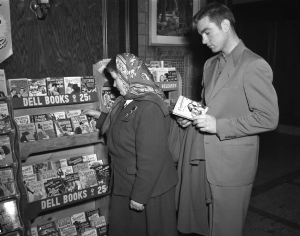 Doris Peterson of Dodgeville, and Niles Ernst of Green Bay, look over the display of pocket editions of books operated by John C. Leonard at the Union Bus Depot.