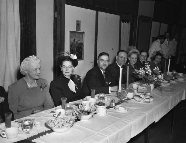 Speaker's table at the annual Lutheran Men's Club "Sweetheart's Dinner" 
held at the Lutheran Memorial Church, 1021 University Avenue. Seated left to right: Mrs. Oscar (Mary) Rennebohm; Mrs. Jerry R. (Elizabeth) Coulter; Jerry A. Coulter, master of ceremonies; Dr. Wesley Wendt, president of the Men's club; Mrs.Florene Wendt; Mrs. Clarence (Ruth) Reuter, and Mrs. John (Sylvia) Gray.