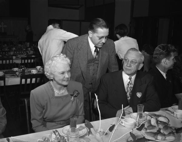 Speaker's table at the annual Lutheran Men's Club "Sweetheart's Dinner" held in the Lutheran Memorial Church, 1021 University Avenue. Seated left to right: Mrs. Oscar (Mary) Rennebohm and Governor Oscar Rennebohm. Standing behind them is the Reverend Charles A. Puls, pastor of the church.
