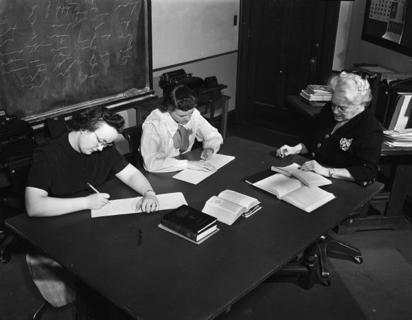 A teacher, probably Mrs. Regina Barnhart at Groves-Barnhart School for Secretaries, giving a shorthand test to two female students.