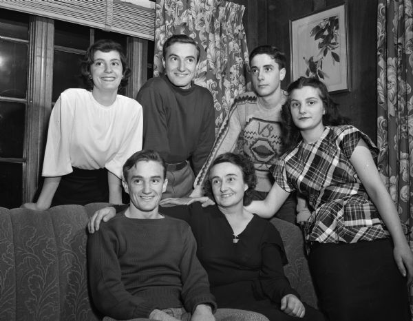 Reunited after seven years of wartime separation, Mrs. Isabel Llerandi and her five younger children spent a week together in the home of Mr. & Mrs. Henry Ramisch, Middleton, loaned to them for the occasion. From left to right they are, seated, Felipe (a university sophomore who lives with Mr. & Mrs. Charles Bunn), Mrs. Llerandi, and Mary (age 16 who lives with Mr. & Mrs Henry Ramisch); standing, Sarita (a university co-ed who lives with Mr. & Mrs Grant Haas), Julian (a university sophomore who lives with Mr. & Mrs. Frank Rentz) and Rogelio (a Central High School junior who lives with Mr. & Mrs. Gilman Page).