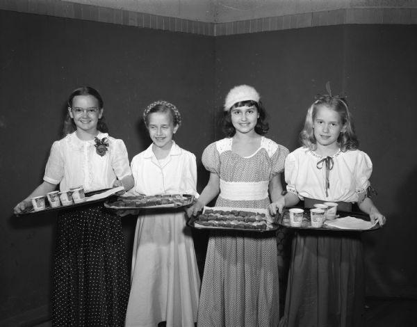 Members of Ethlyn Jefferds' dancing class, fifth and sixth grade students from Shorewood, Randall, and Lakewood schools, attending their first costume ball. Shown are four girls in costume with trays of food, acting as hostesses. Left to right: Jean Sorum, Judy Leidahl, Cynthia Curren and Julie Dunn.