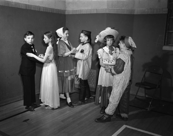 Members of Ethlyn Jefferds' dancing class, fifth and sixth grade students from Shorewood, Randall, and Lakewood schools, attending their first costume ball. Three couples in costume are shown dancing. Left to right: John Buck and Lenore Youngman; Severa Brevik and Larry Washa; and Martha Frautschi and John Neupert.