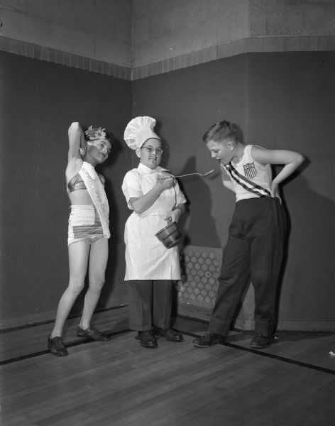 Members of Ethlyn Jefferds' dancing class, fifth and sixth grade students from Shorewood, Randall, and Lakewood schools, attending their first costume ball. Left to right: Ronald Stein, dressed as Miss Shorewood Hill, Ivan Bonser, in a chef costume, and Harry Sauthoff, Jr., dressed as Olympic athlete.