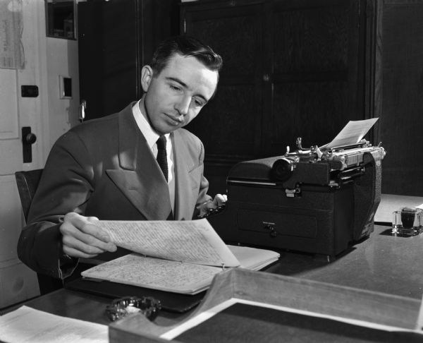U.S. Army Major Hunter Brumfield in a suit and tie at a typewriter examining his notes. Major Brumfield is one of several army officers working on a master's degree in the school of journalism.
